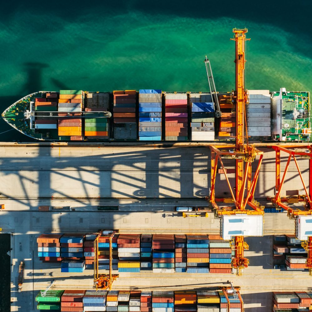 Aerial view of containers loading and unloading to the ship in the sea port. Logistic and transportation of goods. Crisis and shortage of containers in the world.